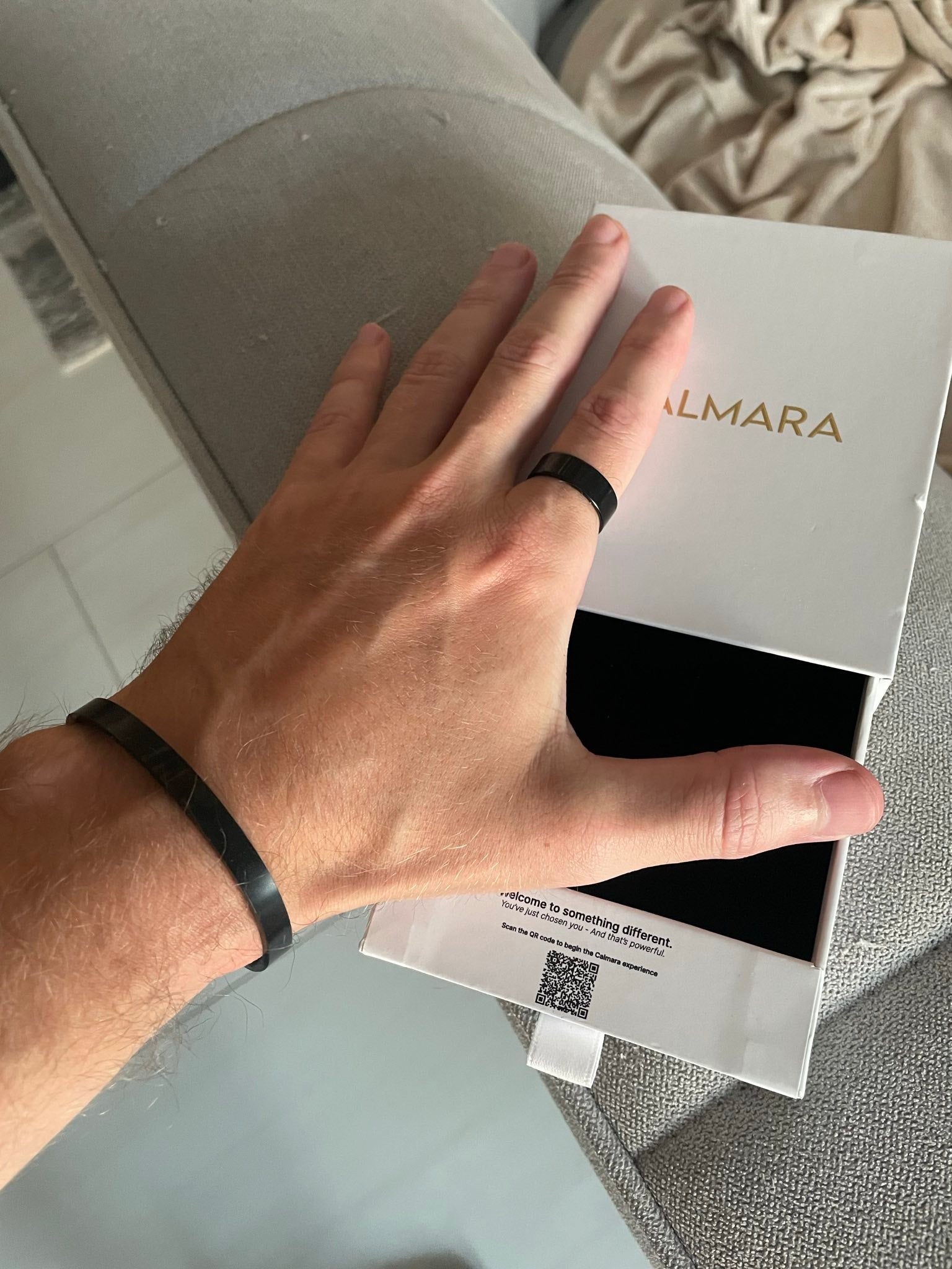 Hand holding a box with 'CALMARA' branding on a neutral background